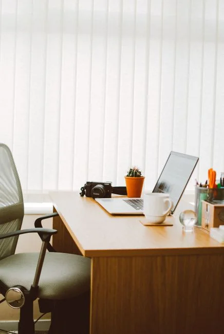 A stylish interior featuring moving boxes marked Kitchen and Office on a wooden table, with houseplants all around.